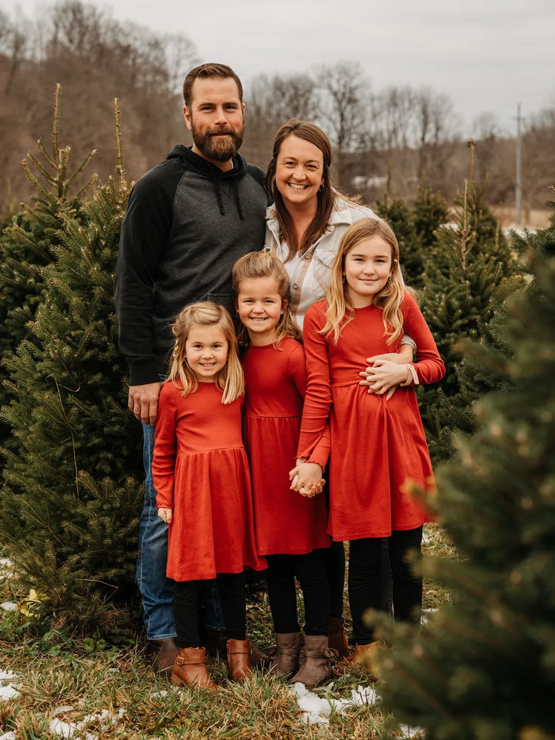 family with small pine trees posing for the camera